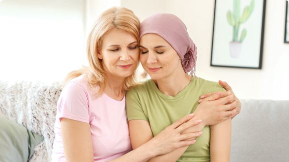 A female cancer patient being embraced by her mother.